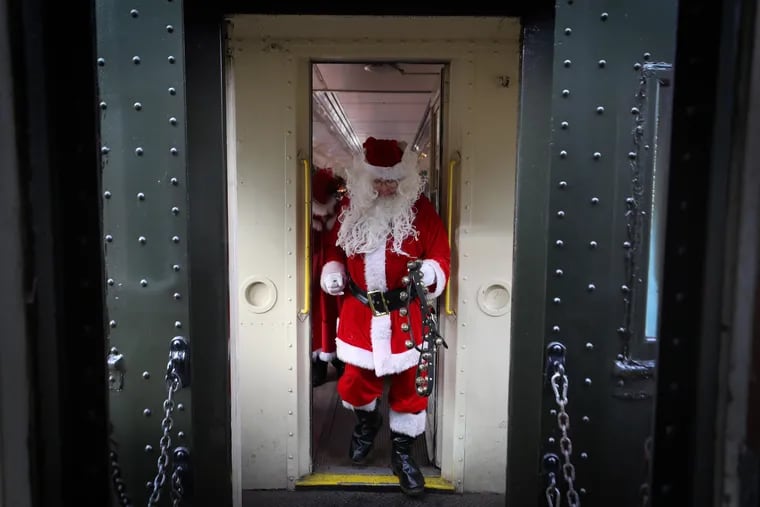 Santa Claus, who was portrayed by Jack Sullivan, walks between cars to visit children.
