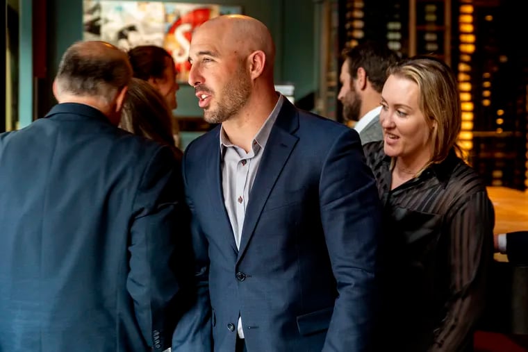 Former Eagle Chris Maragos is with his wife Serah Maragos (right) and his law team at a Center City restaurant following a jury’s verdict against his doctors, ordering them to pay the ex-NFL All-Pro player $43.5 million.