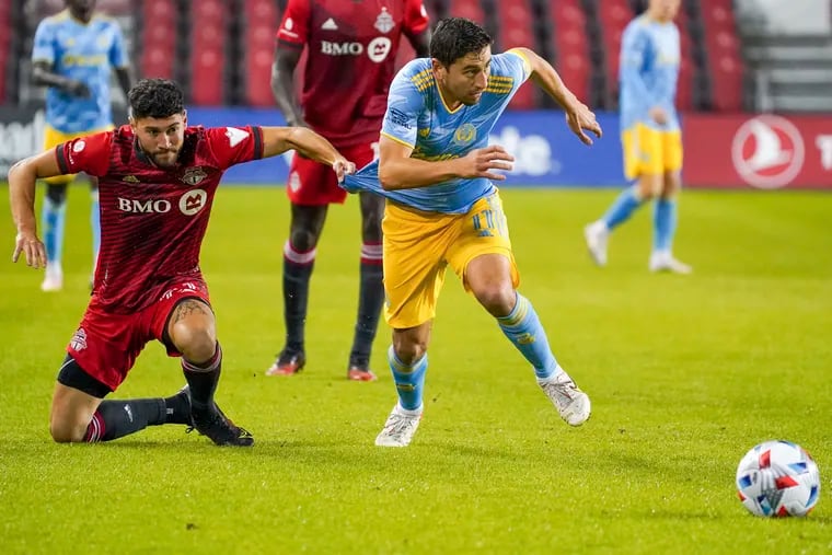 Union midfielder Alejandro Bedoya (center) tries to escape the clutches of Toronto FC midfielder Jonathan Osorio during the first half of Wednesday's 2-2 tie in Toronto.