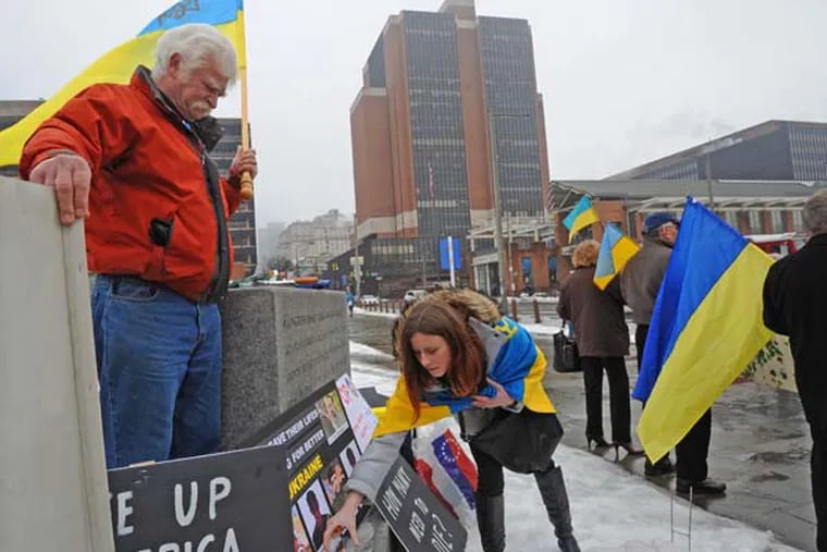 Local Ukrainians hold a mourner's vigil on Independence Mall in Philadelphia on  Feb. 19, 2014.  Here, Yulia Kurka places a candle in memory of those killed; at left is Basil Panczak. ( APRIL SAUL  / Staff )