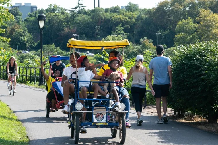 Kahlid Henry, 7, front left, and Kahleel Henry, 7, front right, sit in the front of a group cycle with their dog Mister P, while their sister Kiajah Henry, 12, back left, and mother Kiahfa Evans, back right, pedal the cycle, on Kelly Drive, on a beautiful Labor Day in Philadelphia, Monday, September 7, 2020.  JESSICA GRIFFIN / Staff Photographer
