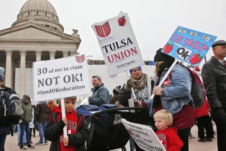 Keagan Nedrow (left) and Reed Nedrow (bottom right) stand with their mother, Tara Nedrow (right), who teaches history at Union High School, and other teachers, during an April 2 teacher rally against low school funding at the state Capitol in Oklahoma City.
