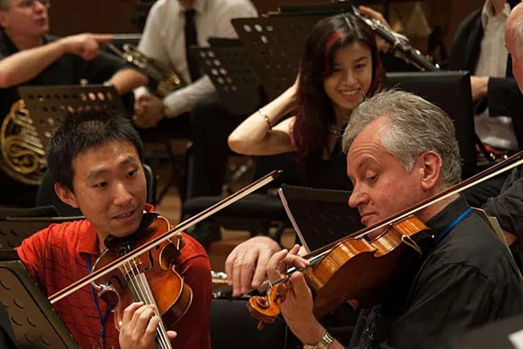 Philadelphia Orchestra violinist Dimitri Levin (right) and a member of the Shanghai City Symphony go over a part in rehearsal for a joint concert. (Jan Regan/The Philadelphia Orchestra)