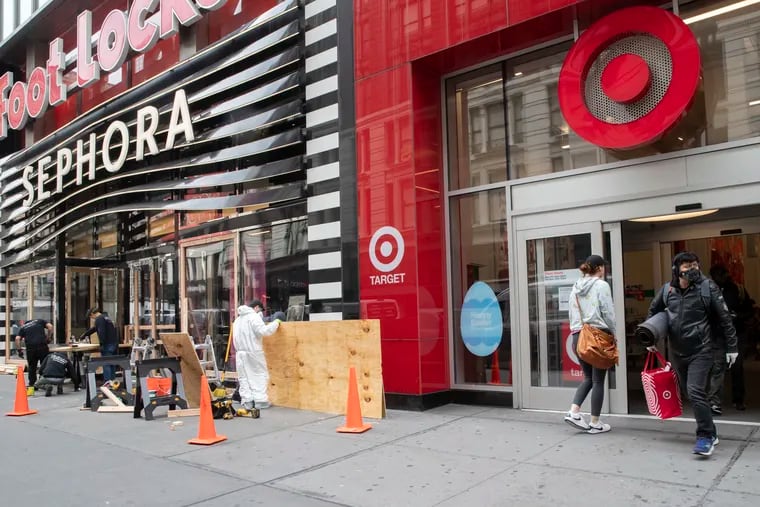 A shopper leaves the Target Store on 34th St. in New York as carpenters board up Sephora Friday, March 20. Target Corp. said it will give a $2 an hour wage increase, in effect at least through May 2, to its 300,000-plus workers who have been scrambling to help customers.