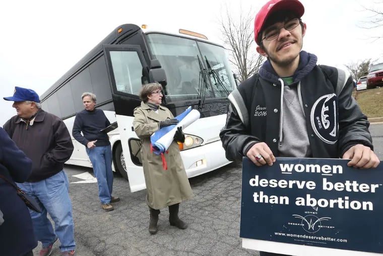 Jesse Davis holds a sign before boarding a bus in Winchester, Va., for the March for Life rally.
