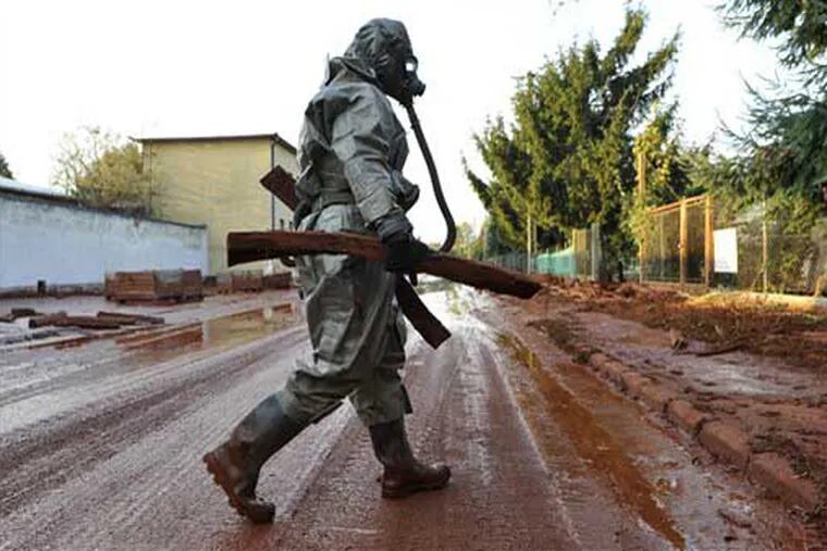 A Hungarian soldier, wearing a chemical protection gear, cleans a street flooded by toxic in the town of Devecser, Hungary, Tuesday, Oct. 5, 2010. Monday's flooding was caused by the rupture of a red sludge reservoir at an alumina plant in western Hungary and has affected seven towns near the Ajkai Timfoldgyar plant in the town of Ajka, 100 miles (160 kilometers) southwest of Budapest. (AP Photo/Bela Szandelszky)