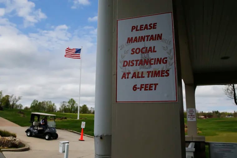 A sign reminding golfers and employees to maintain social distancing hangs on at The Golf Course at Glen Mills on Friday, the first day golf courses in Pennsylvania were allowed to reopen.