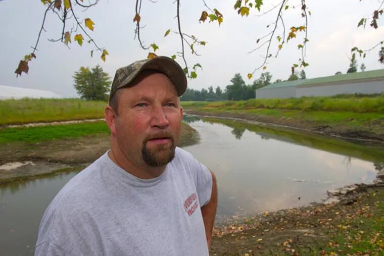 George Cassaday stands by a nearly empty irrigation pond on his Monroeville farm. (AVI STEINHARDT/ For The Inquirer)