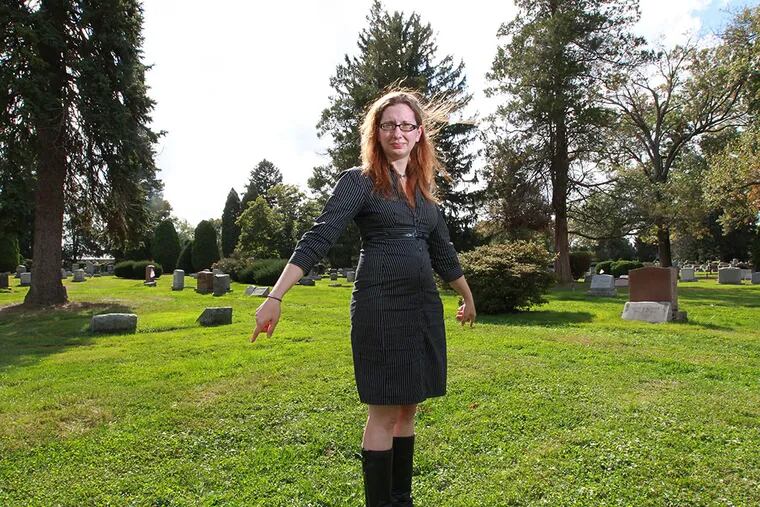 Megan Harris, archivist at Arlington, stands over the ground where the bodies of over 120 immigrants from Lazaretto Quaratine Station in Tinicum are buried at Arlington Cemetery. There is no marker. ( MICHAEL BRYANT  / Staff Photographer )