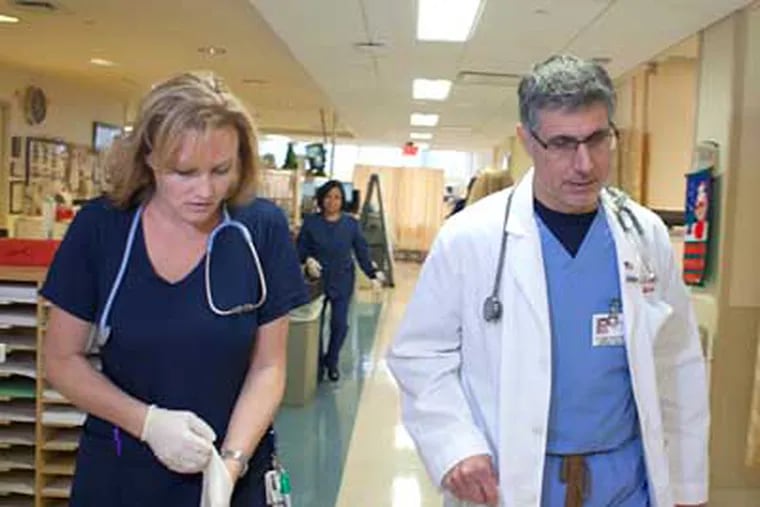 Dr. Alfred Sacchetti and nurse Erica Frampton work in the ER at Our Lady of Lourdes Medical Center in Camden, where procedures have been changed to improve patient flow. (ED HILLE / Staff Photographer)