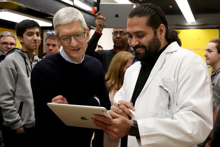 Apple CEO Tim Cook, center, being shown the app to dissect a frog on an IPad. Cook is a bargain of CEO according to Bloomberg’s Pay Index.
