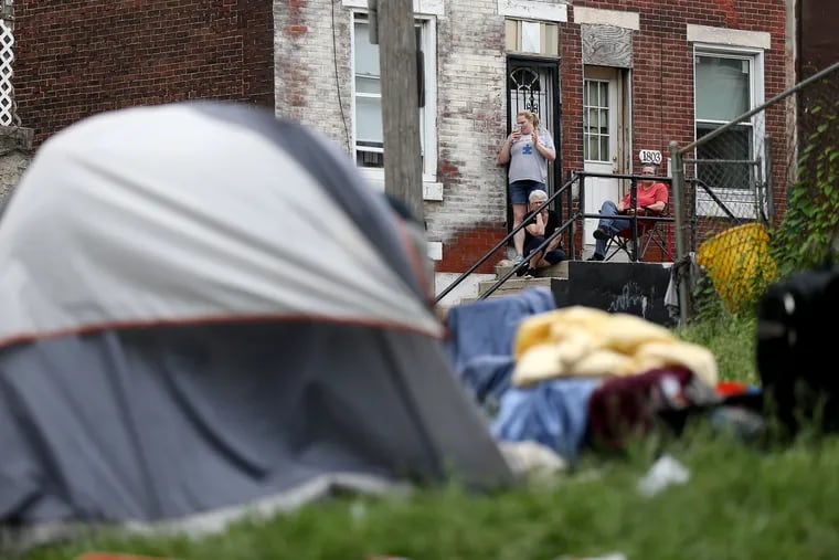 Neighbors watch as police begin to evict people living at the Kensington Avenue encampment, one of two of Kensington's heroin camps, in Philadelphia, PA on May 30, 2018.