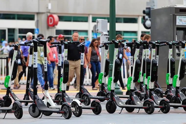 A large number of rental scooters are parked near the Convention Center along 5th Avenue in San Diego in July 2018.