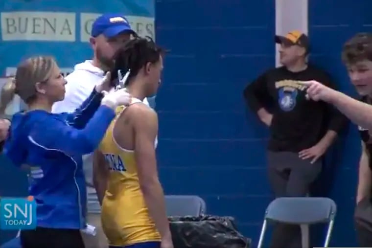 In this Dec. 19, 2018, file image, made from a video provided by SNJTODAY.COM, Buena (N.J.) Regional High School wrestler Andrew Johnson gets his haircut courtside minutes before his match, after a referee told Johnson he would forfeit his bout if he didn't have his dreadlocks cut off. Alan Maloney, the referee who insisted that Johnson cut his hair, has been suspended for two seasons.