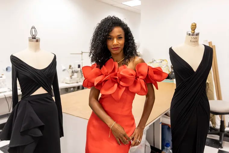 Jeanette Limas, a designer who was a part of Season 3 of “Making the Cut”, poses with two of her popular draped dresses for a portrait in the Philadelphia Fashion Incubator studio.
