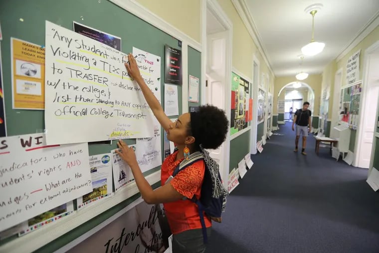 Keyanna Ortiz-Cedeno, 21, a junior who participated in a sit-in protest at Swarthmore College earlier this month, adjusts her sign outside of  the office of Associate Dean of Students Nathan Miller.