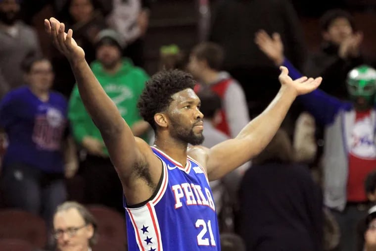 Joel Embiid of the Sixers raises his arms as he leaves the game in the final minute.