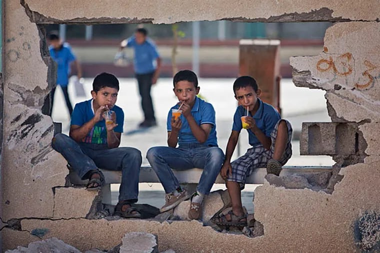 In Gaza City's Shijaiyah neighborhood, schoolboys drink iced juice as they sit on a damaged wall of a school.