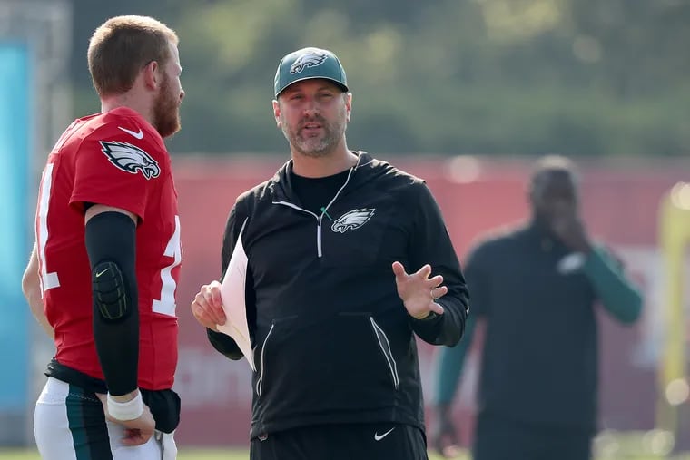 Eagles offensive coordinator Mike Groh (right) talking with Carson Wentz during training camp in July.