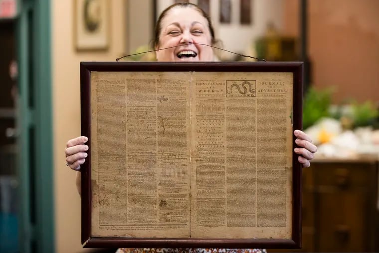 FILE - In this Thursday, Oct. 25, 2018 file photo, Heather Randall displays a Dec. 28, 1774 Pennsylvania Journal and the Weekly Advertiser at the Goodwill Industries South Jersey in Bellmawr, N.J.  An original 1774 Philadelphia newspaper that was discovered at a New Jersey Goodwill is heading to a Philadelphia philosophy society founded by Benjamin Franklin.