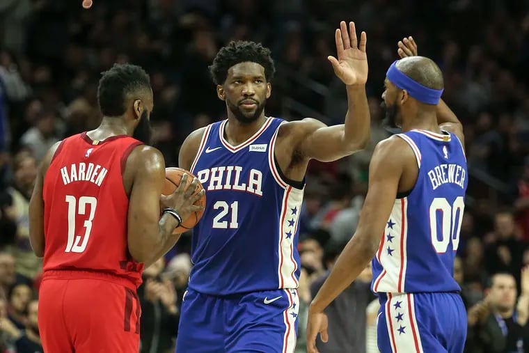 Sixers' Joel Embiid celebrating with teammate Corey Brewer next to the Rockets' James Harden on Monday night.