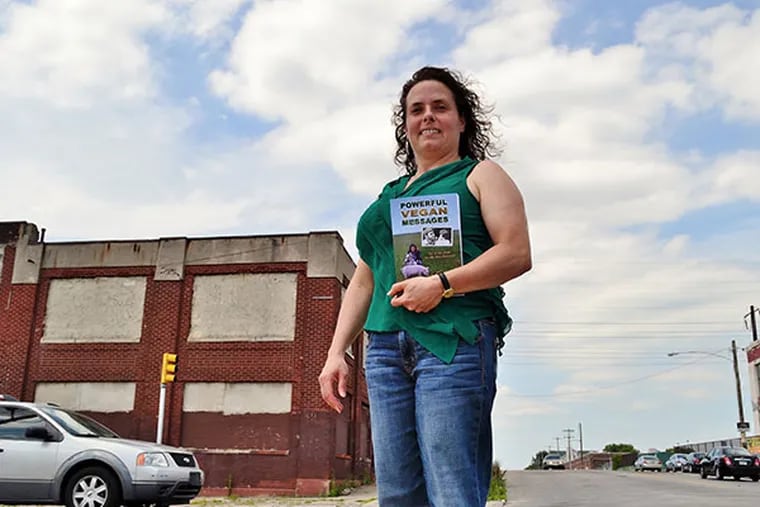 Anne Dinshah stands holding her new book "Powerful Vegan Messages" in front of the now closed Cross Bros. Meat Packing Co. on Monday, June 30, 2014.  (C.F. Sanchez / Staff Photographer)