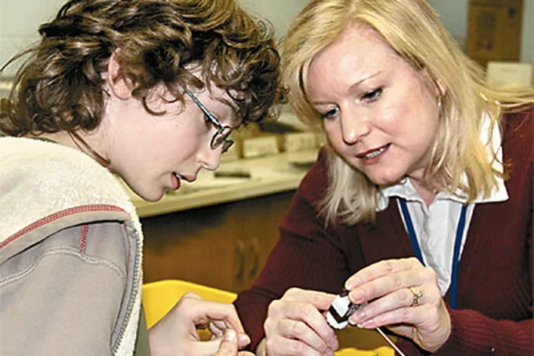 Thirteen percent of Cheltenham Township students are classified as gifted. Beth Kenna (right) works with a student in her gifted class, building a solar-powered car at Cedarwood Middle School. (John Costello/Inquirer)