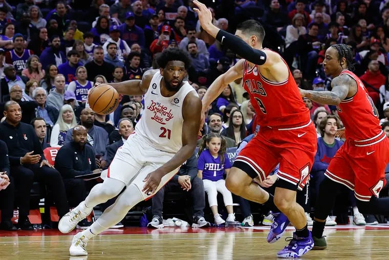 Sixers center Joel Embiid dribbles the basketball against Chicago Bulls center Nikola Vucevic and forward DeMar DeRozan on Monday, March 20, 2023 in Philadelphia.