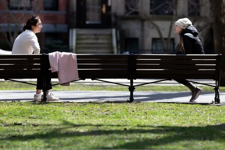 Two women practice social distancing while talking on Commonwealth Avenue Mall in Boston on Saturday.