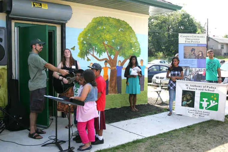 Anna Perkins of Camden Churches Organized for People leads a song about peace at the dedication of the mural at Von Nieda Park in Cramer Hill.
