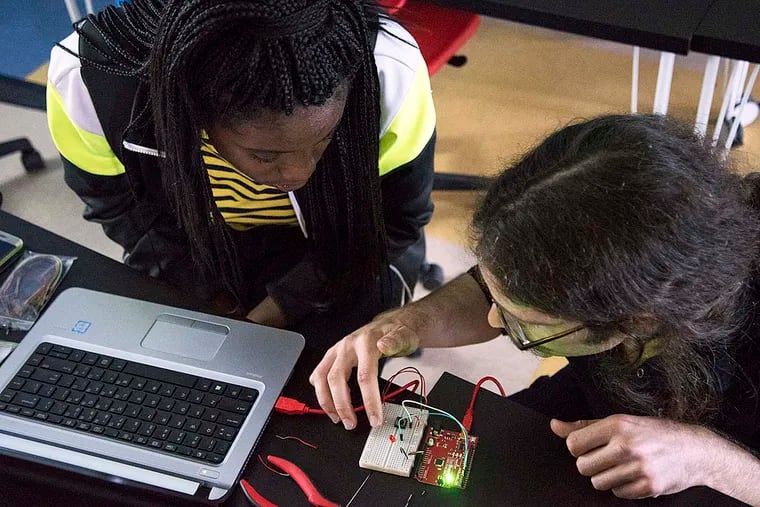 At Roxborough High School, Onyea Cropper, 16, and her instructor Jeff Gregorio work on a “breadboard” using Arduino software.