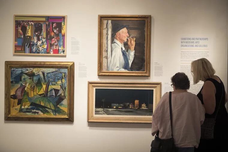 Two women look over part of a new exhibit at the Michener Museum in Doylestown featuring art owned by various school districts, including Philadelphia’s.