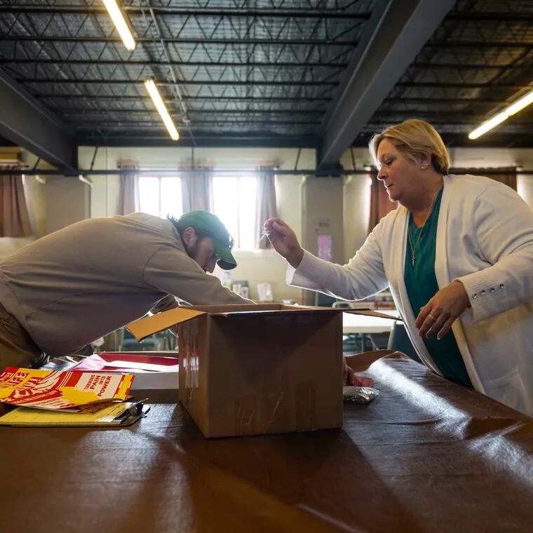 Kim Botteicher organizes supplies with coworker David Peightal in the church basement offices of FAVOR ~ Western PA in Bolivar, Pa. The nonprofit helps families struggling with addiction find housing, jobs, and other recovery supports.