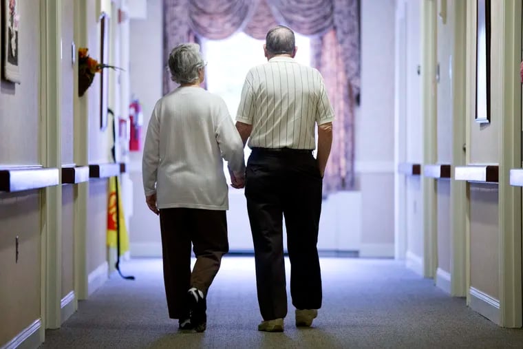 FILE photo shows an elderly couple walking down a hall of a nursing home in Easton, Pa.
