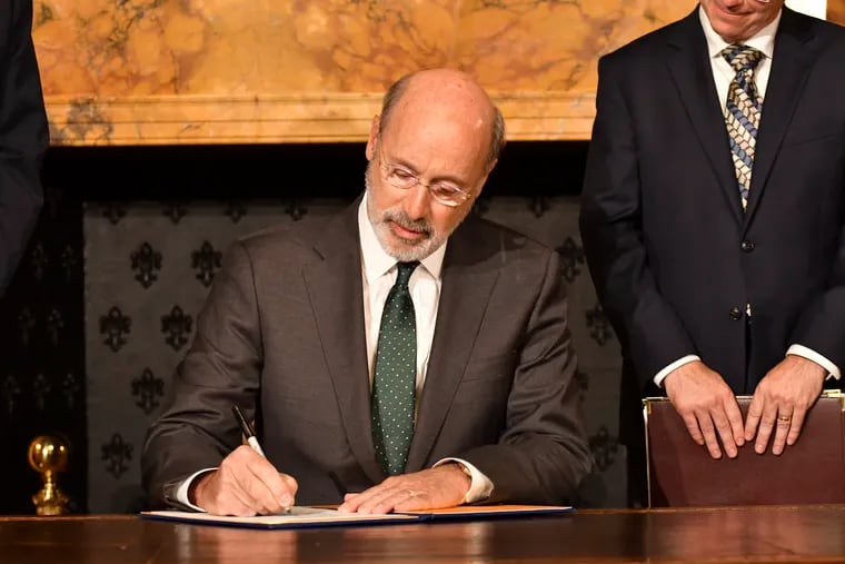 Gov. Tom Wolf signs an executive order for his administration to start working on regulations to bring Pennsylvania into a nine-state consortium that sets a price and limits on greenhouse gas emissions from power plants, Oct. 3, 2019, in Harrisburg.