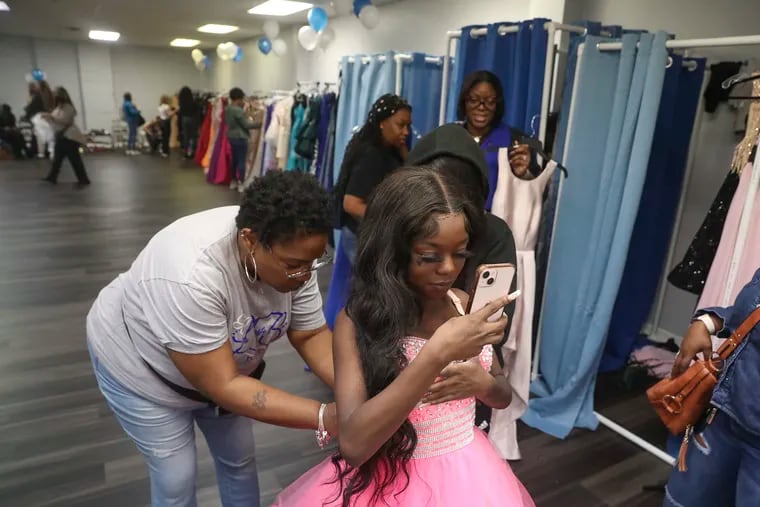 Kimberly Drake helps Liyani Moody try on a prom gown at a free event at Promenade Reception Hall in Philadelphia. For many Philly families, prom costs remain high, often between $300 and $1,000.
