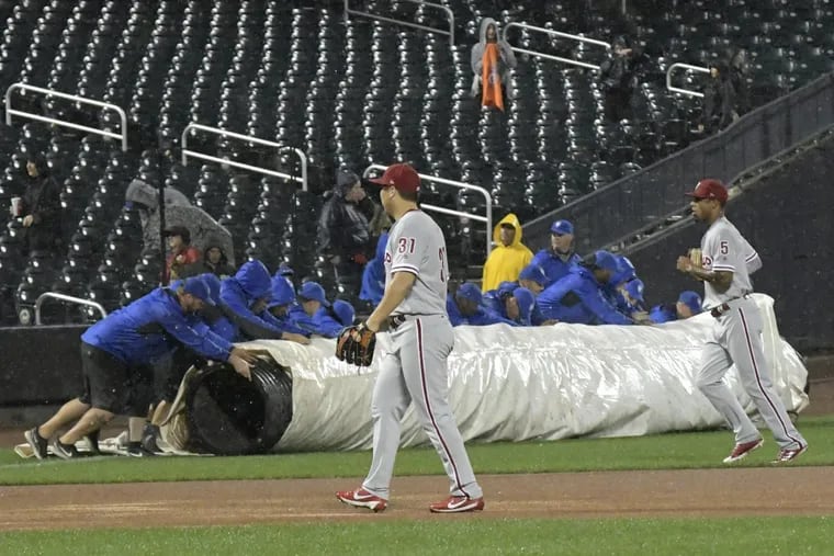 Phillies outfielders Hyun Soo Kim left and Nick Williams walk off the field as the grounds crew rolls out the tarp for a rain delay during the sixth inning. The game did not resume.