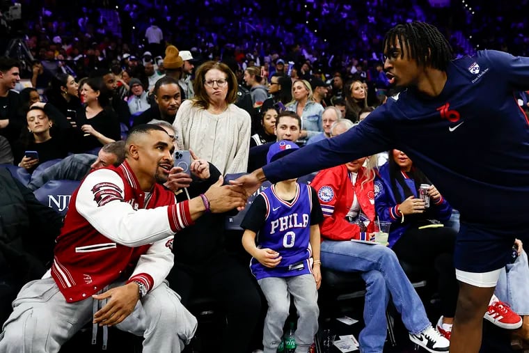 Sixers guard Tyrese Maxey greets Eagles quarterback Jalen Hurts during a break from Monday's game.