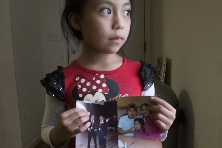 The 7-year-old daughter of a jailed undocumented immigrant holds family photos.