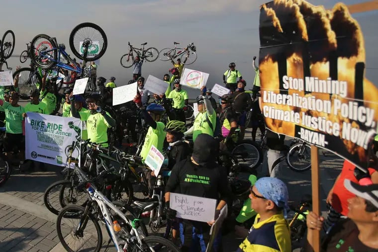 Filipinos raise their bicycles as they join a rally in Manila, Philippines. Nearly 200 nations adopted the first global pact to fight climate change on Saturday.