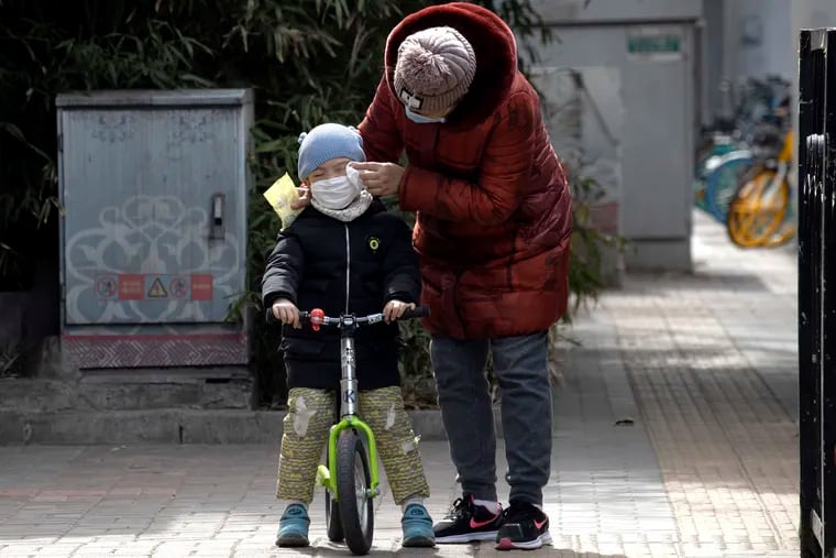 A woman wipes the face of a child on the streets of Beijing on Thursday, March 12, 2020. Chinese officials kept the public in the dark about COVID-19 until late January, while people moved freely in and out of Wuhan. China lacks a free press to spread the word. Had the Chinese public learned about the outbreak sooner, we might not be facing the current crisis.