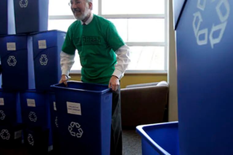 Donald J. Farish, president of Rowan University, hands out recycling bins. Rowan announcedit would move to single-stream recycling, which allows various recyclables to go in one bin.