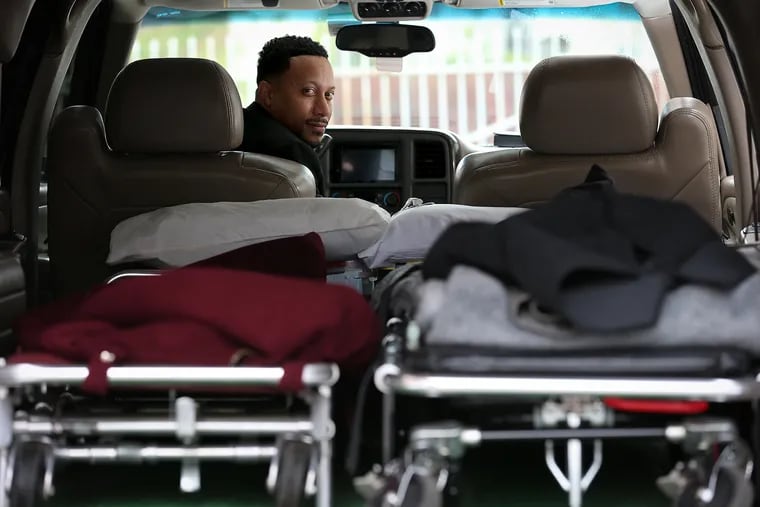 Preston Griffin, who runs First Class Mortuary Transport, poses for a portrait inside his vehicle after delivering a body to the Alfonso Cannon Funeral Chapels.
