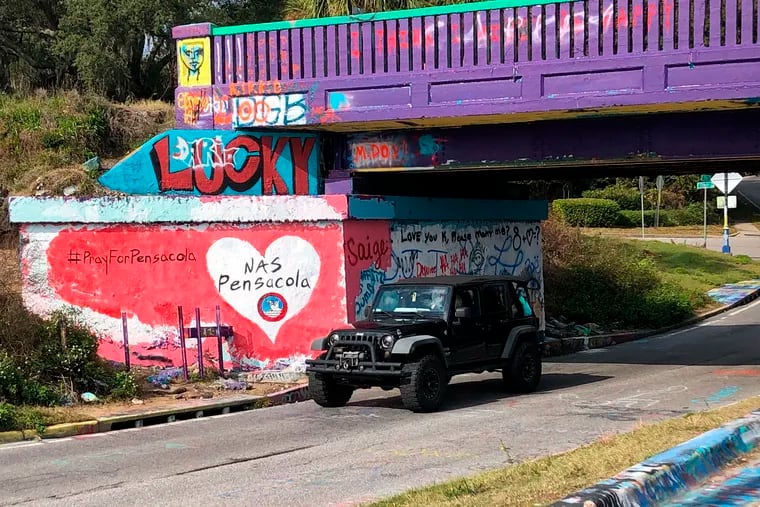 A vehicle drives by a tribute to victims of the Naval Air Station Pensacola that was freshly painted on what’s known as Graffiti Bridge in downtown Pensacola, Fla., on Saturday, Dec. 7, 2019.  A US official says the Saudi student who fatally shot three people at the Florida naval base had hosted a dinner party earlier in the week to watch videos of mass shootings. The official spoke on condition of anonymity after being briefed by federal investigators. The official says a second Saudi student was recording outside the building at the Naval Air Station Pensacola on Friday while the shooting was happening inside. The official also says 10 Saudi students are being held at the base and that several others are unaccounted for.