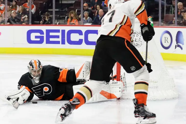 Flyers rookie goaltender Carter Hart lays on the ice with the puck against Anaheim left winger Nick Ritchie during a 6-2 win over the Ducks on Saturday.
