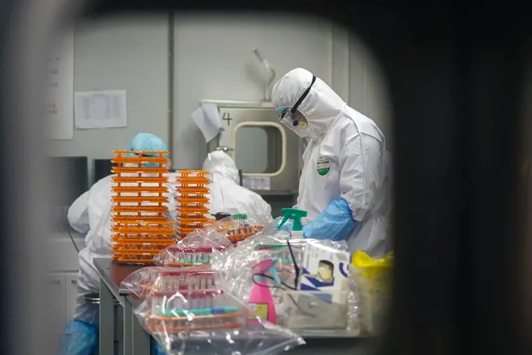 Medical workers in protective suits work on diagnostic testing of throat swabs and other fluid samples at a coronavirus detection lab in Wuhan, China, the epicenter of the outbreak.
