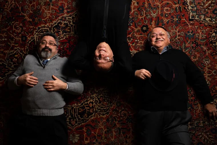 Benjamin, Youda and Reuben Tehrani lie down on one the Persian rugs at their store in Bryn Mawr.