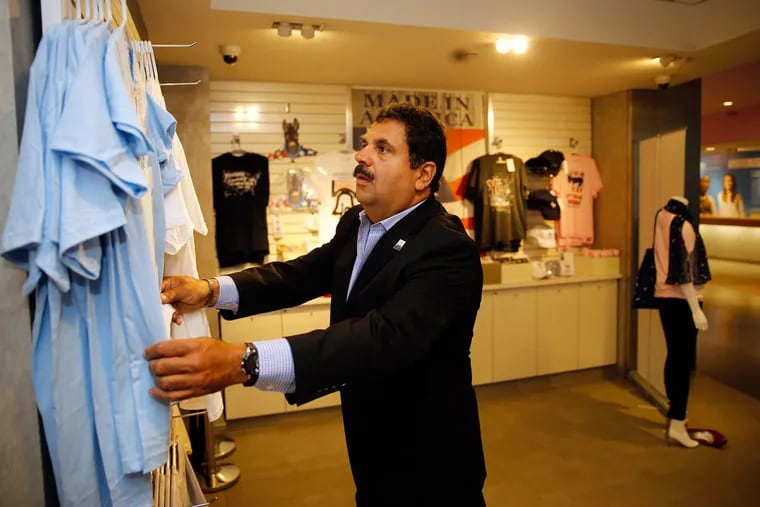 Luis Liceaga, majority partner of Impact Dimensions, adjusts T-shirts in his gift shop at the Comcast Tower.