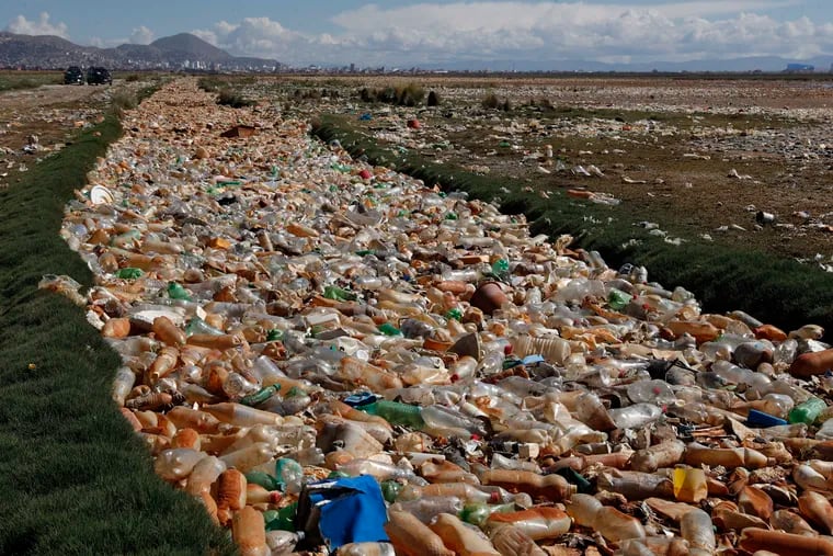 Plastic bottles and other garbage floats on the Tagaret River which flows into Uru Uru Lake, near Oruro, Bolivia on March 25, 2021. A large majority of DuPont's investors wants the chemical giant to say how much plastic it puts out each year. (AP Photo/Juan Karita)