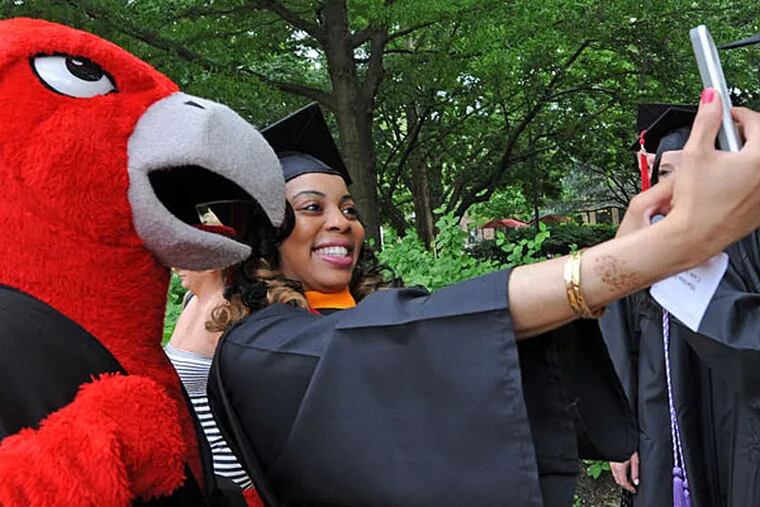 Martina Hohney, 26, takes her photo with the Rutgers-Camden mascot, a scarlet raptor, at the nursing school commencement ceremonies in May 2013 at the university's Walter K. Gordon Theater in Camden.